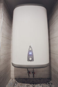 Instant tankless electric water heater installed on white tile wall with input and output pipe outlet and elcb safety breaker system.