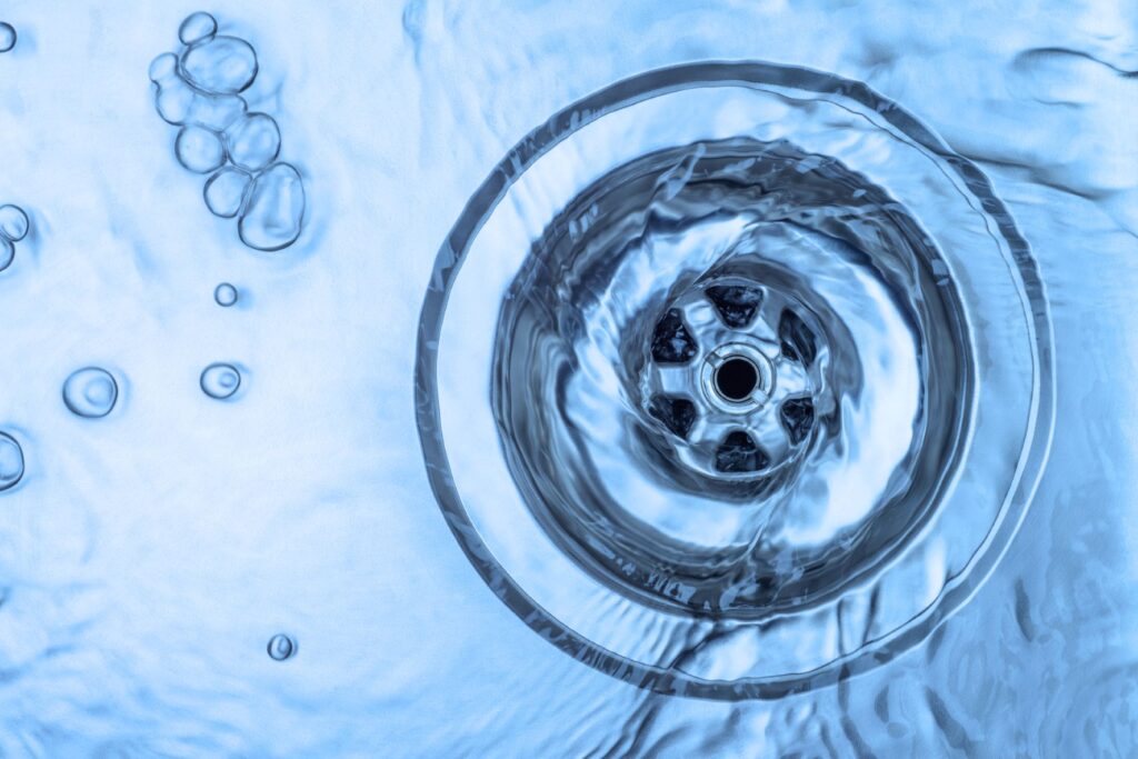 Close view of water funneling down a sink drain.