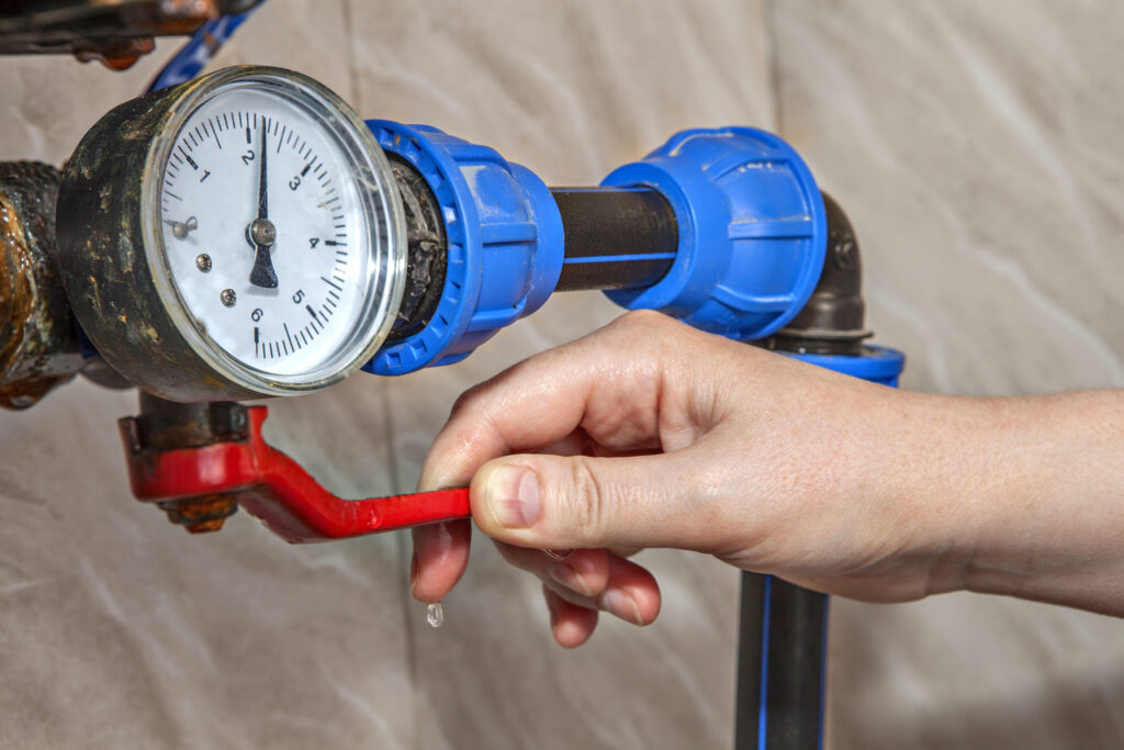 Hand holding lever next to gauge on main water shut off.