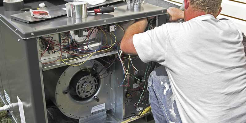 Technician repairing an outdoor AC unit.