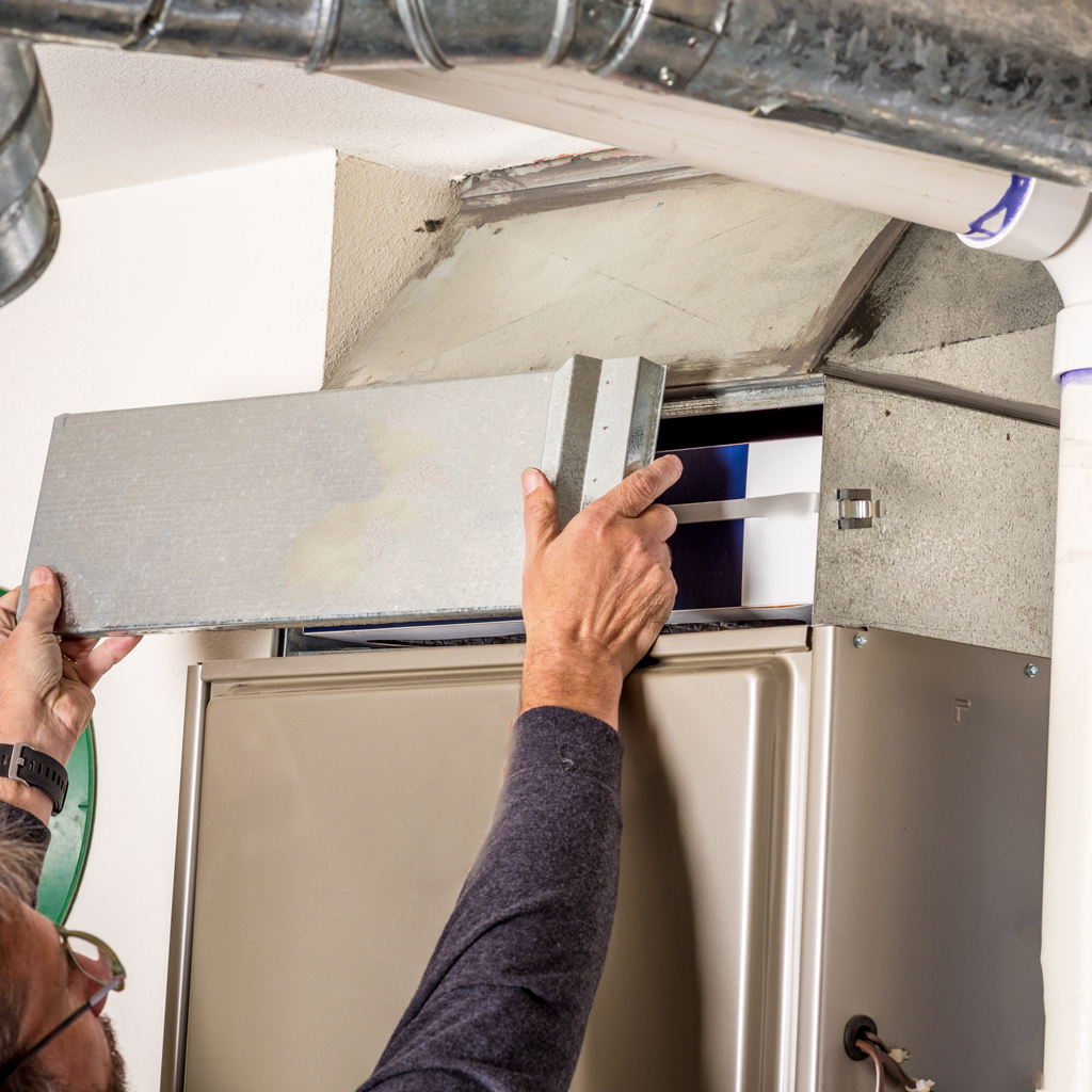 Technician removing the furnace filter cover to inspect it.